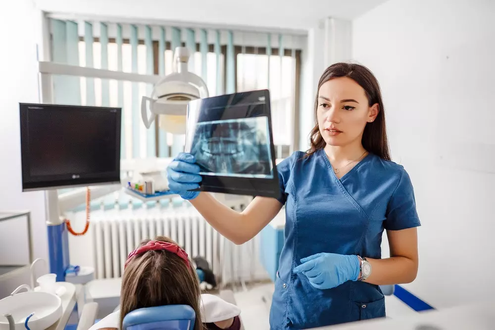 stomatolog trzymająca zdjęcie rentgenowskie zębów pacjentki